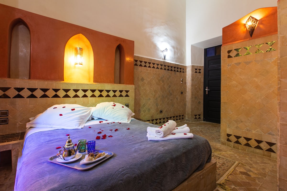 A hotel room with a bed, a tray with breakfast items, and a shower area.