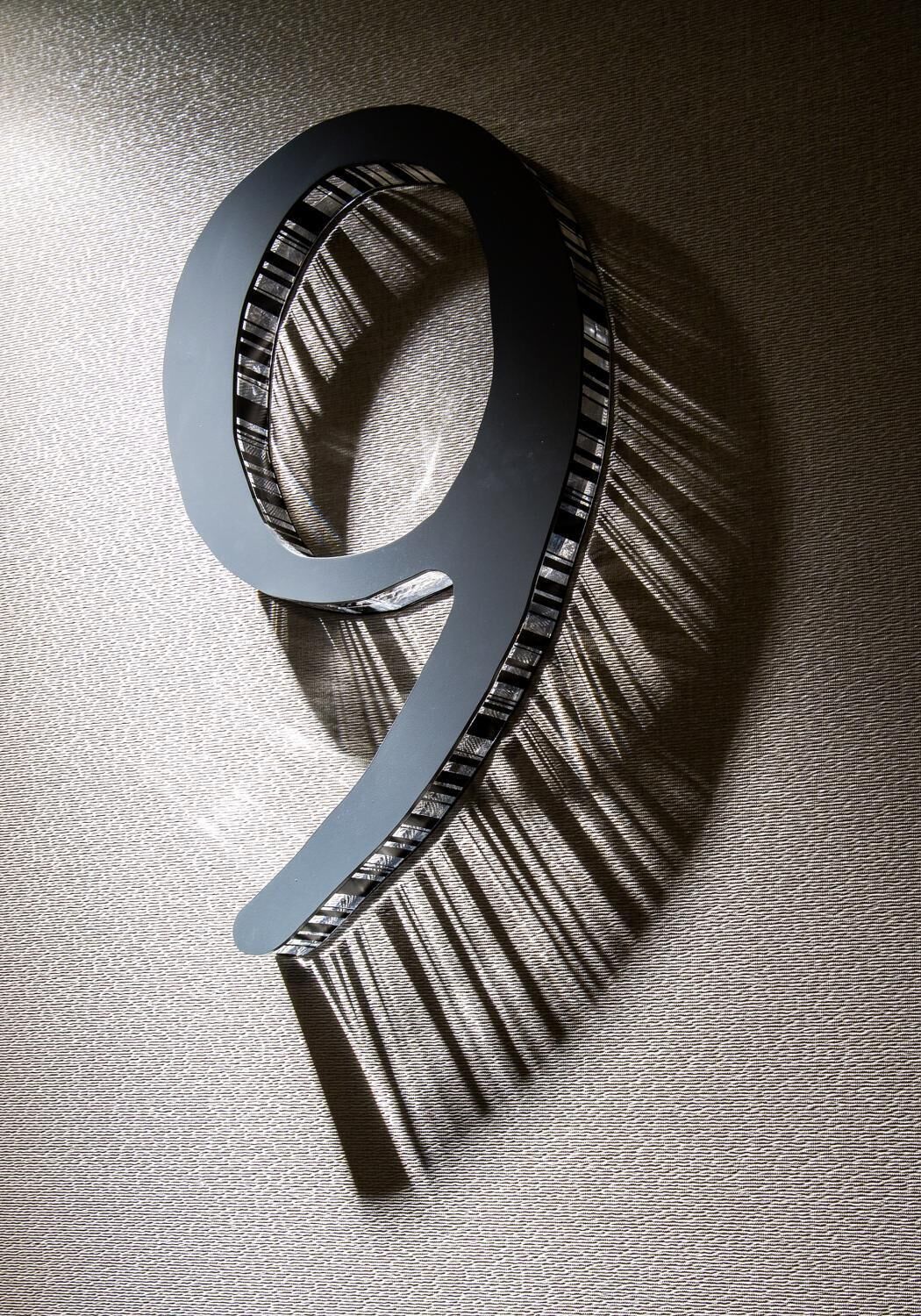 A large, metallic number '9' on a textured surface.