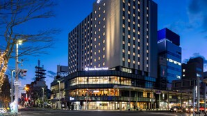 Un hotel Daiwa Roynet con fachada de vidrio moderna, varios pisos y señalización iluminada.