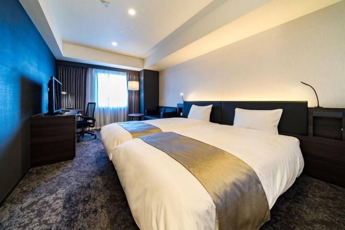 Una habitación de hotel con una cama grande, un escritorio, una silla y un televisor.