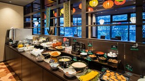 Zona de bufé con diferentes opciones de comida, una máquina de café y faroles decorativos.