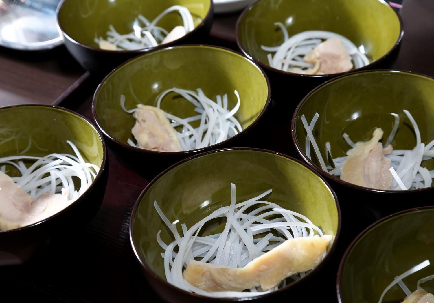 Bowls containing shredded white vegetables and pieces of meat.