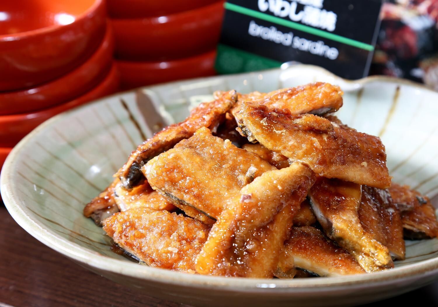A plate of fried chicken wings with a glossy coating, served on a ceramic dish.