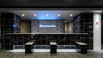 A reception area with a marble wall, a digital display for the Dalwa Roynet Hotel, and a reception desk.