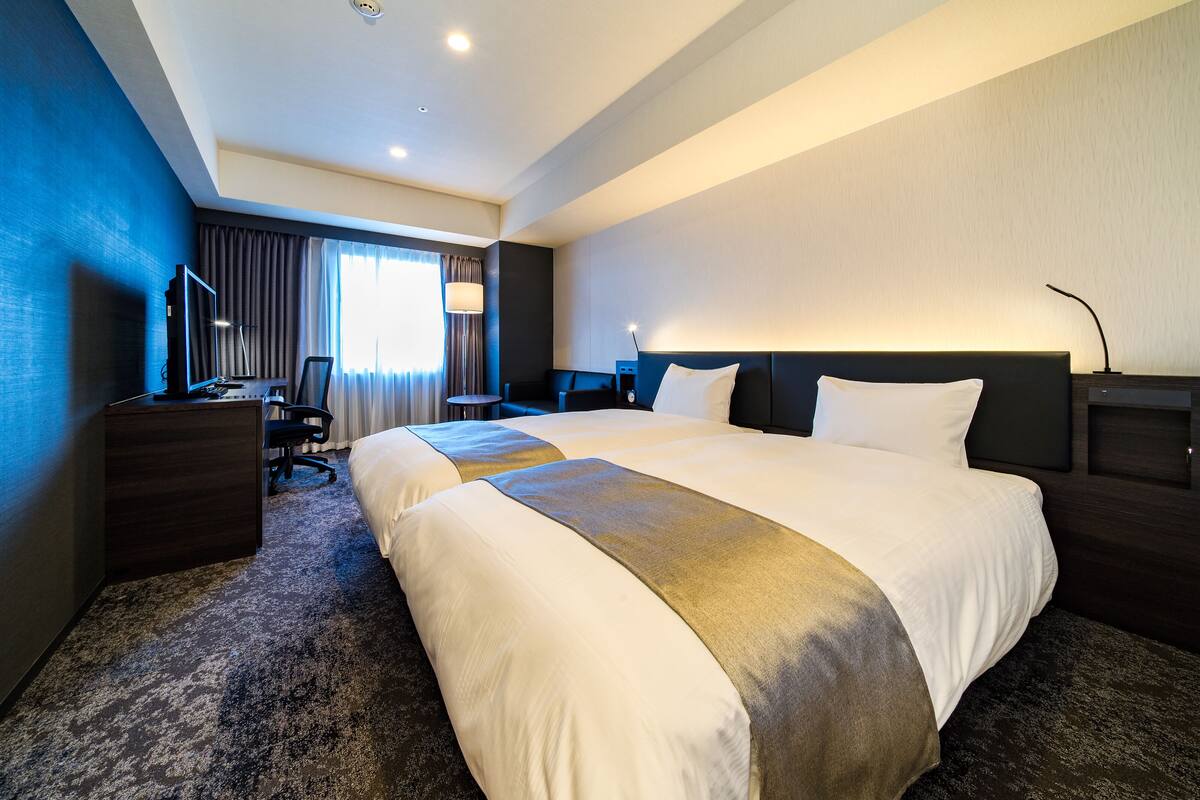Habitación de hotel con una cama grande, un escritorio con computadora, una silla y un televisor.