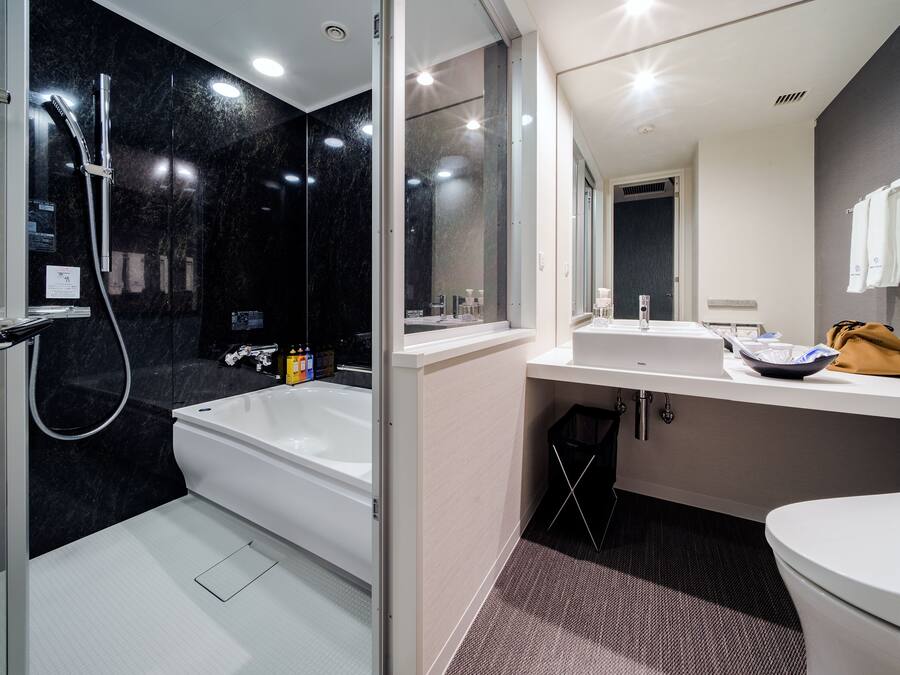 A modern bathroom with a bathtub, a shower, a sink, and a toilet.