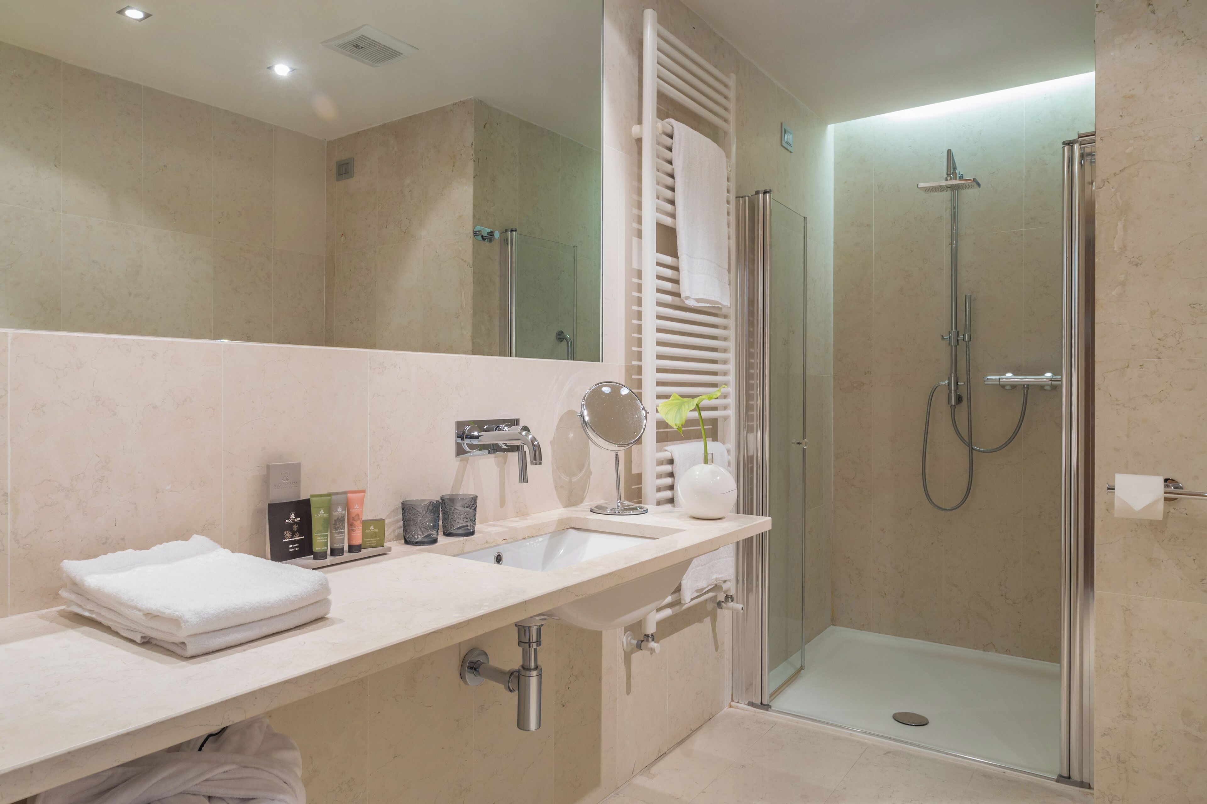Un bagno moderno con uno specchio grande, un lavandino e una zona doccia.