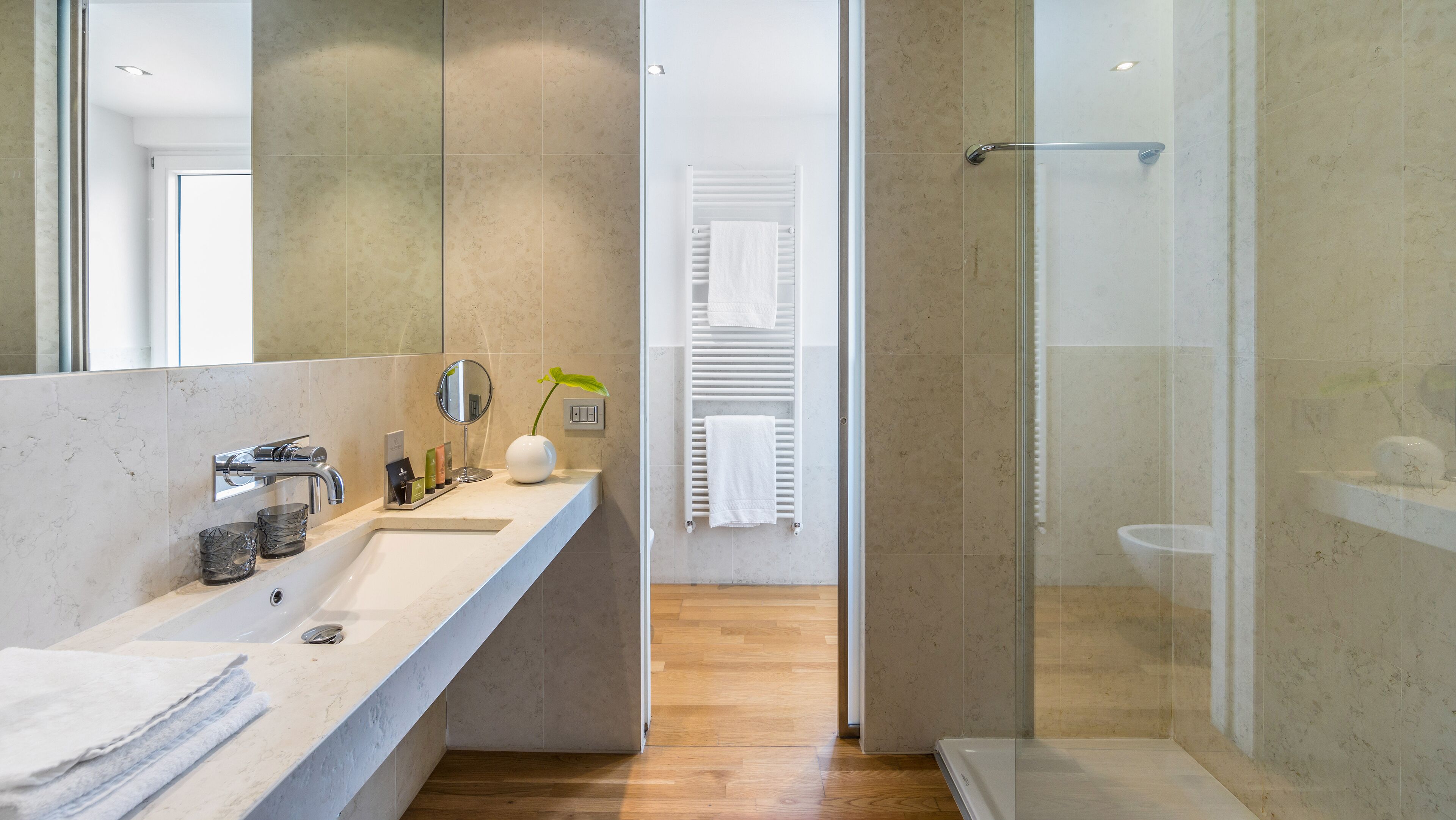 Une salle de bain moderne avec un grand miroir, un lavabo blanc et une cabine de douche en verre.