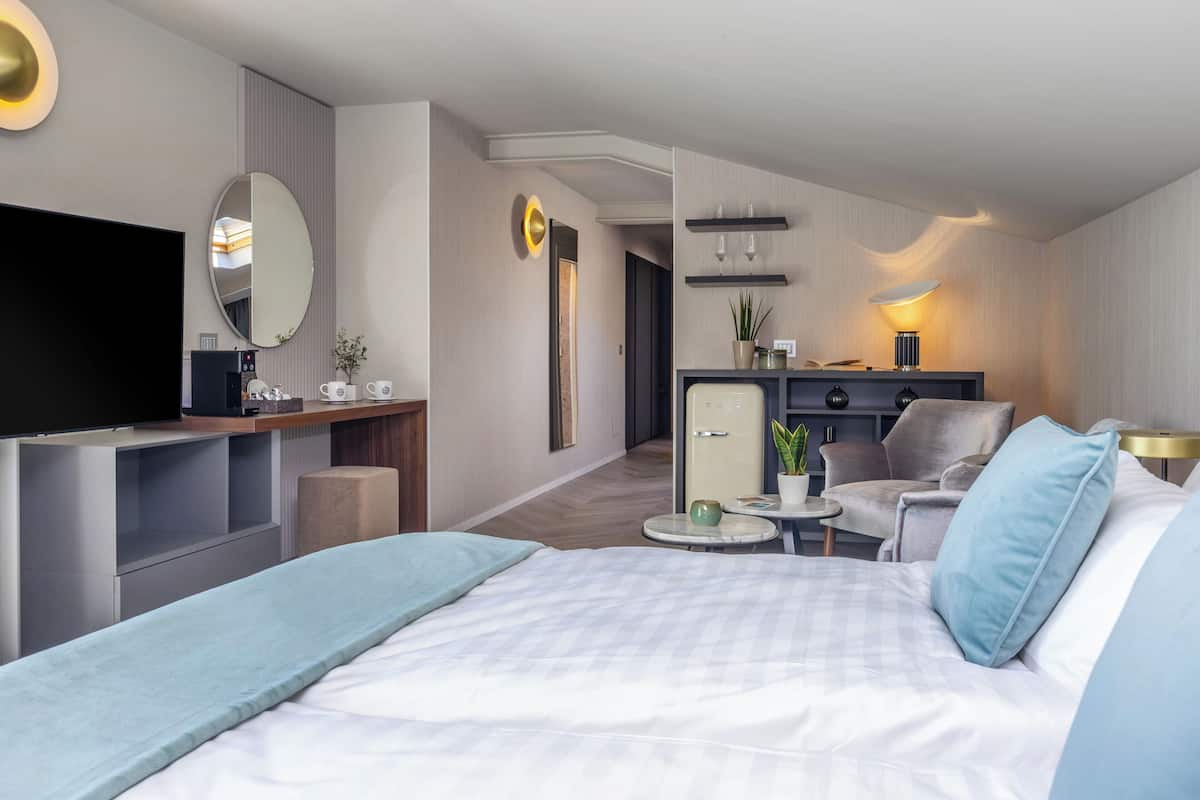 Een moderne hotelkamer met een groot bed, een televisie, een bureau en een zithoek met een stoel en een kleine tafel.