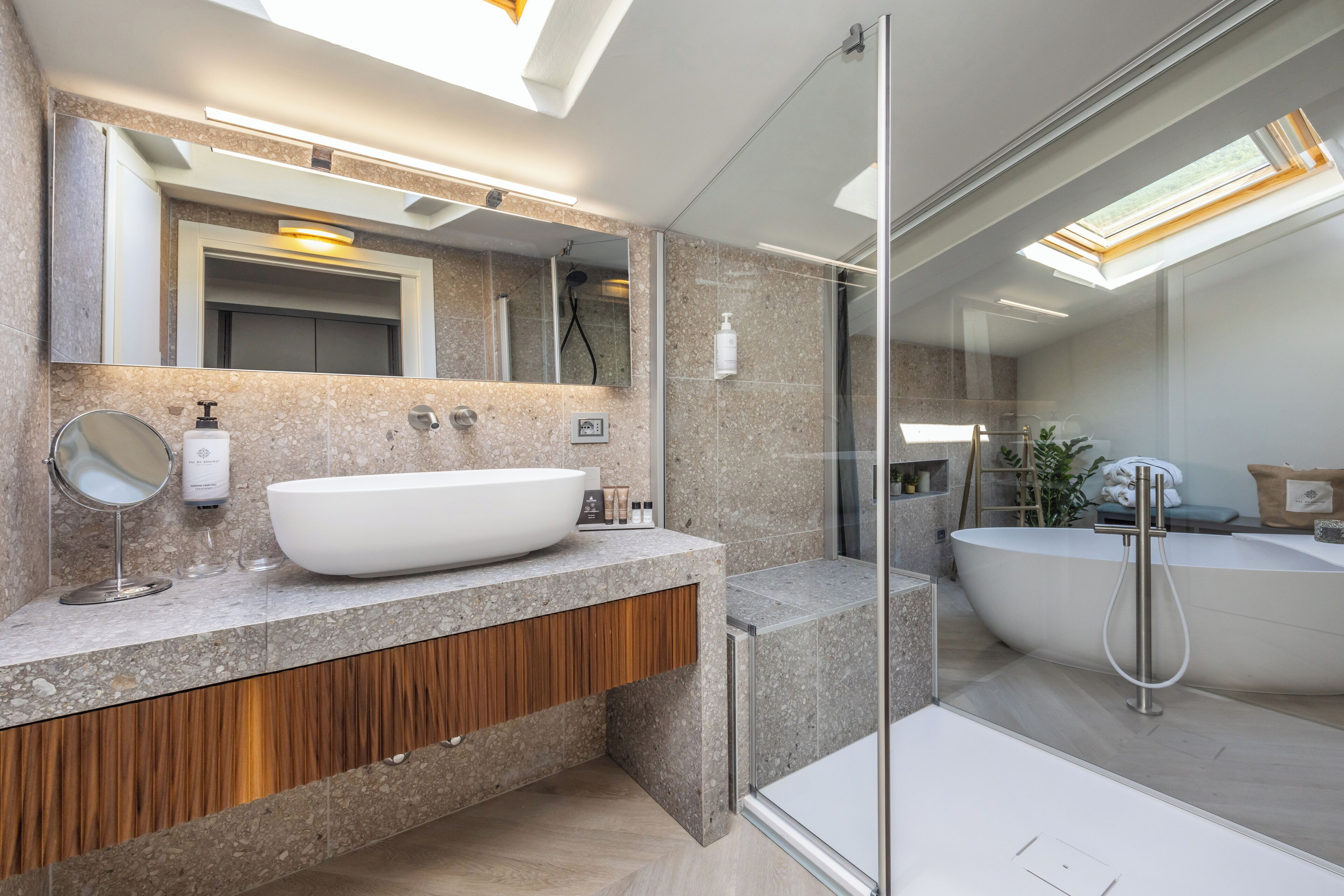 A modern bathroom with a large freestanding bathtub, a glass-enclosed shower, and a vanity with a large mirror and sink.