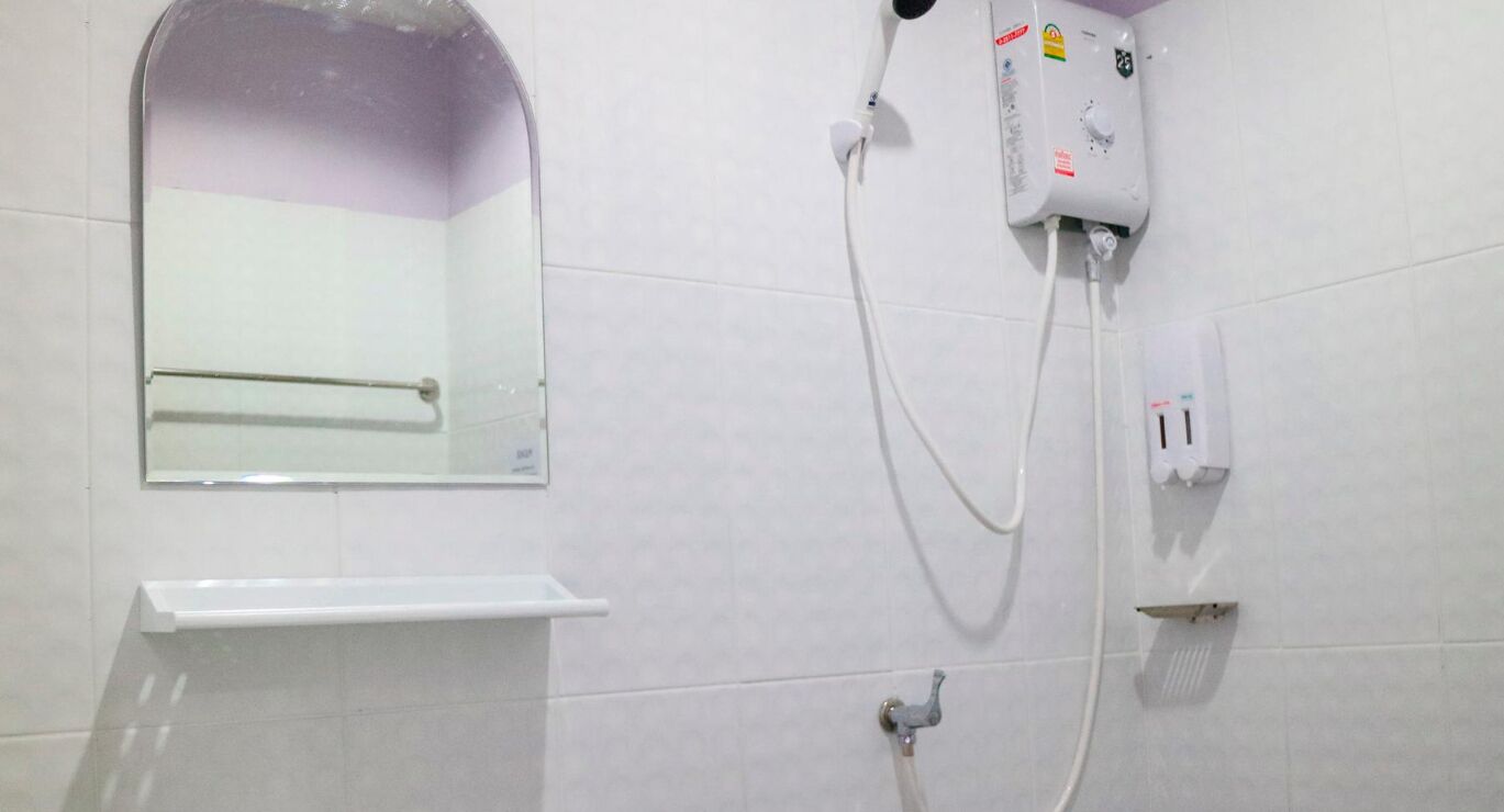 Un baño con ducha, espejo y barra para toallas.