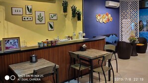 Un restaurante con mostrador de madera, fotografías enmarcadas y pared azul con un diseño decorativo.