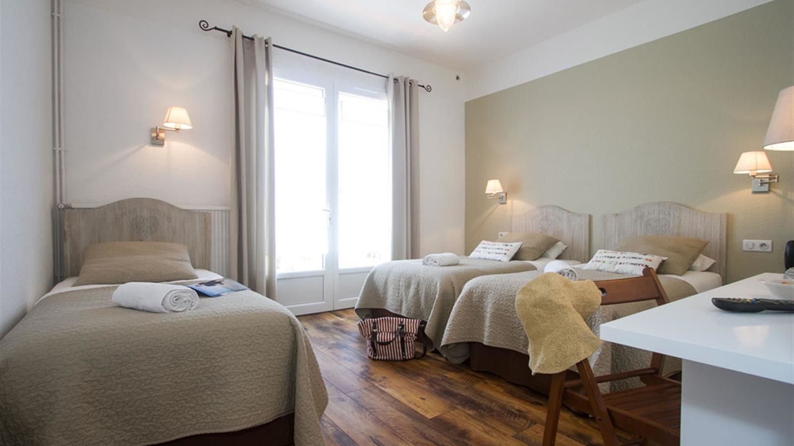 Hotellihuoneessa on kaksi sänkyä, työpöytä ja tuoli. Huoneessa on myös kaksi yöpöytävalaisinta ja ikkuna, jossa on verhot.