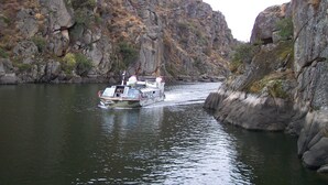 Un bote navegando por un cañón estrecho flanqueado por riscos escarpados.