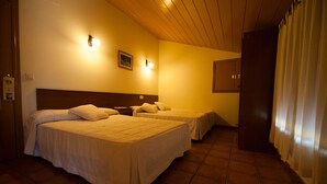 Habitación de hotel con dos camas, techo de madera y suelo de baldosas.