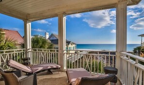 A covered balcony with wicker furniture, a view of the beach and ocean, and a clear sky. - Caribbean Paradise 4 Bedroom Holiday Home by Five Star Properties (Miramar Beach)