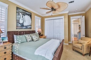 A bedroom with a bed, a ceiling fan, a painting of swans, and a chair. - Caribbean Paradise 4 Bedroom Holiday Home by Five Star Properties (Miramar Beach)