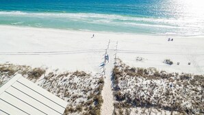 En strand med en sandstig som leder ner till vattnet, en vit byggnad och en fri utsikt över havet.