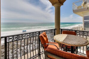 A balcony with a view of the beach, a round table, and orange chairs. - Casa de Cielo 4 Bedroom Holiday Home by Five Star Properties (Destin)