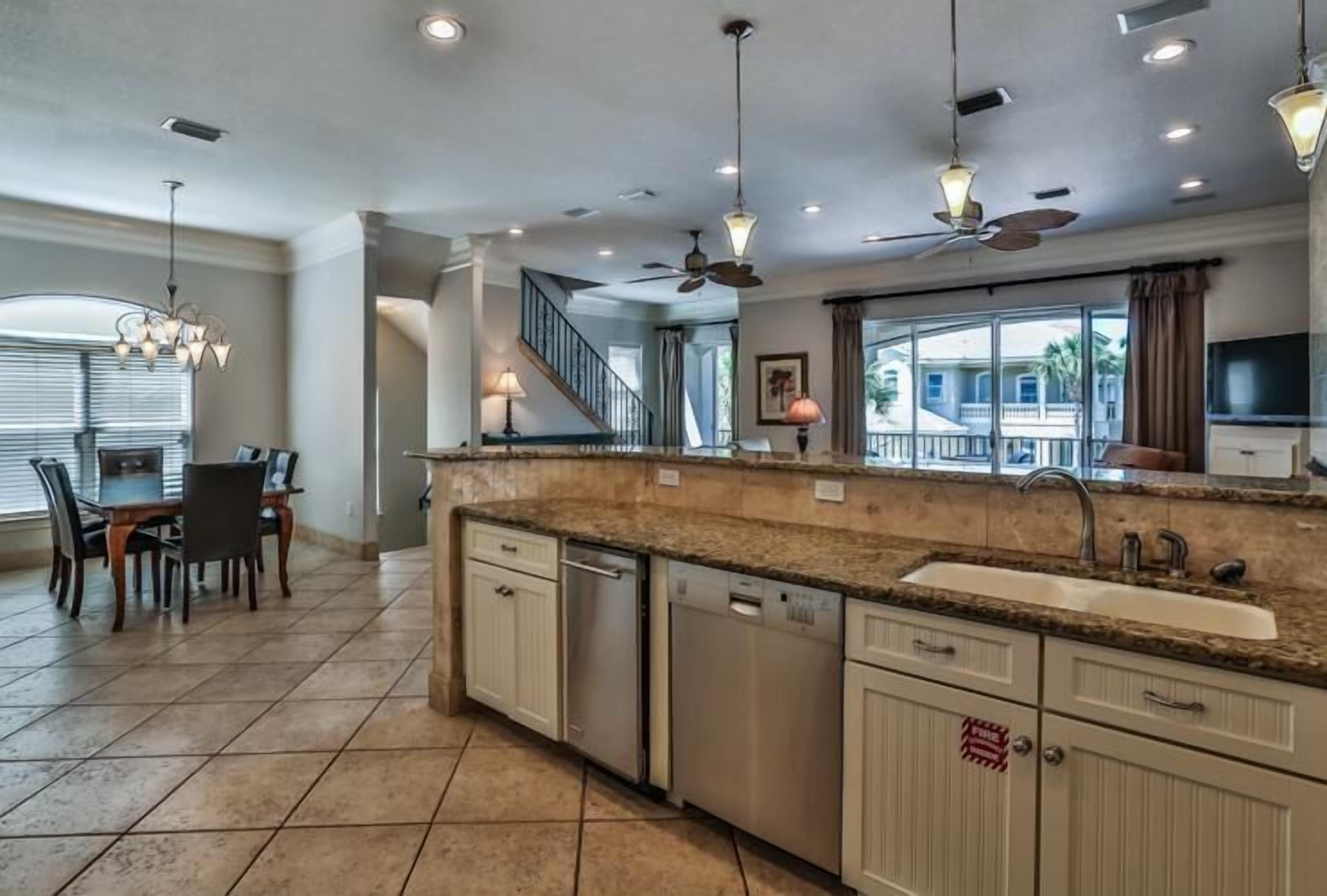 A spacious kitchen with granite countertops, stainless steel appliances, and a large window offering a view of the outdoors.