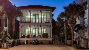A two-story building with large windows and a balcony. - Casa di Tramonto 6 Bedroom Holiday Home by Five Star Properties (Destin)