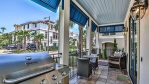 A covered outdoor patio with a grill, seating area, and a view of neighboring houses. - Casa di Tramonto 6 Bedroom Holiday Home by Five Star Properties (Destin)