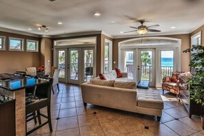 A spacious living area with a sofa, a dining table, and a kitchen area. There are large windows and a balcony with a view of the ocean. - Casa Lontano 3 Bedroom Holiday Home by Five Star Properties (Destin)