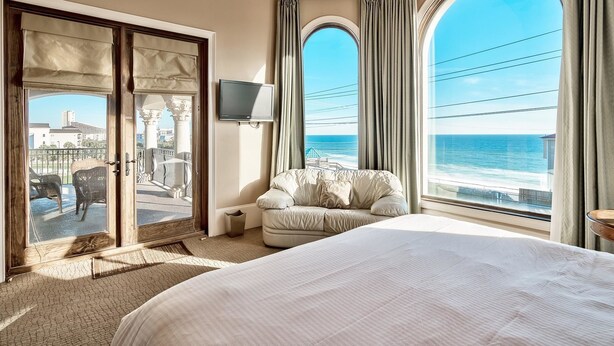 Une chambre d’hôtel avec un grand lit, une télévision et un balcon offrant une vue sur l’océan.