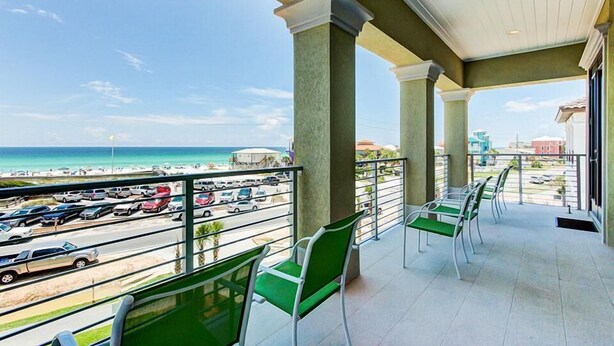 A balcony with green chairs overlooking a beach and parking area. - DaShells30A 6 Bedroom Holiday Home by Five Star Properties (Santa Rosa Beach)