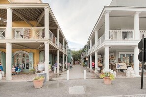 A street with colonial-style buildings, outdoor seating, and potted plants. - Desire 4 Bedroom Holiday Home by Five Star Properties (Santa Rosa Beach)