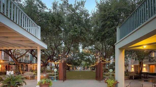 A courtyard with a central lawn, surrounded by trees and potted plants. - Desire 4 Bedroom Holiday Home by Five Star Properties (Santa Rosa Beach)
