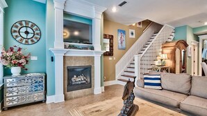 Ein Wohnzimmer mit Kamin, Treppe und einer Wanduhr.