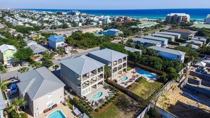 A coastal residential area with multiple houses, a large building with a swimming pool, and a view of the ocean. - Destination Fun 9 Bedroom Holiday Home by Five Star Properties (Destin)