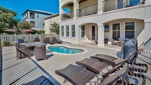 A pool area with lounge chairs and a table, surrounded by a deck and a building with balconies. - Destination Fun 9 Bedroom Holiday Home by Five Star Properties (Destin)