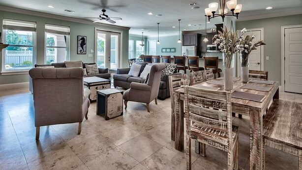 A spacious living room with a large dining table, comfortable seating, and a kitchen in the background. - Destination Fun 9 Bedroom Holiday Home by Five Star Properties (Destin)