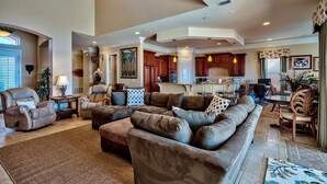 A spacious living room with a large sectional sofa, a fireplace, and a kitchen in the background. - Destiny Tranquility 5 Bedroom Holiday Home by Five Star Properties (Destin)