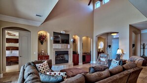 A spacious living room with a fireplace, leather sofas, and a high ceiling. - Destiny Tranquility 5 Bedroom Holiday Home by Five Star Properties (Destin)