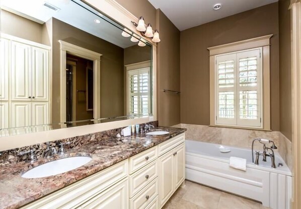 Une salle de bain avec deux lavabos, un grand miroir et une baignoire.