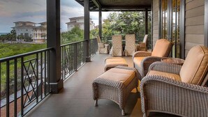 A covered outdoor seating area with wicker furniture and a view of surrounding buildings. - Dream Weaver 5 Bedroom Holiday Home by Five Star Properties (Santa Rosa Beach)