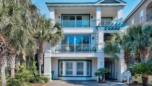 A two-story building with a balcony on the second floor, surrounded by palm trees. - Emerald Enchantment 4 Bedroom Holiday Home by Five Star Properties (Destin)