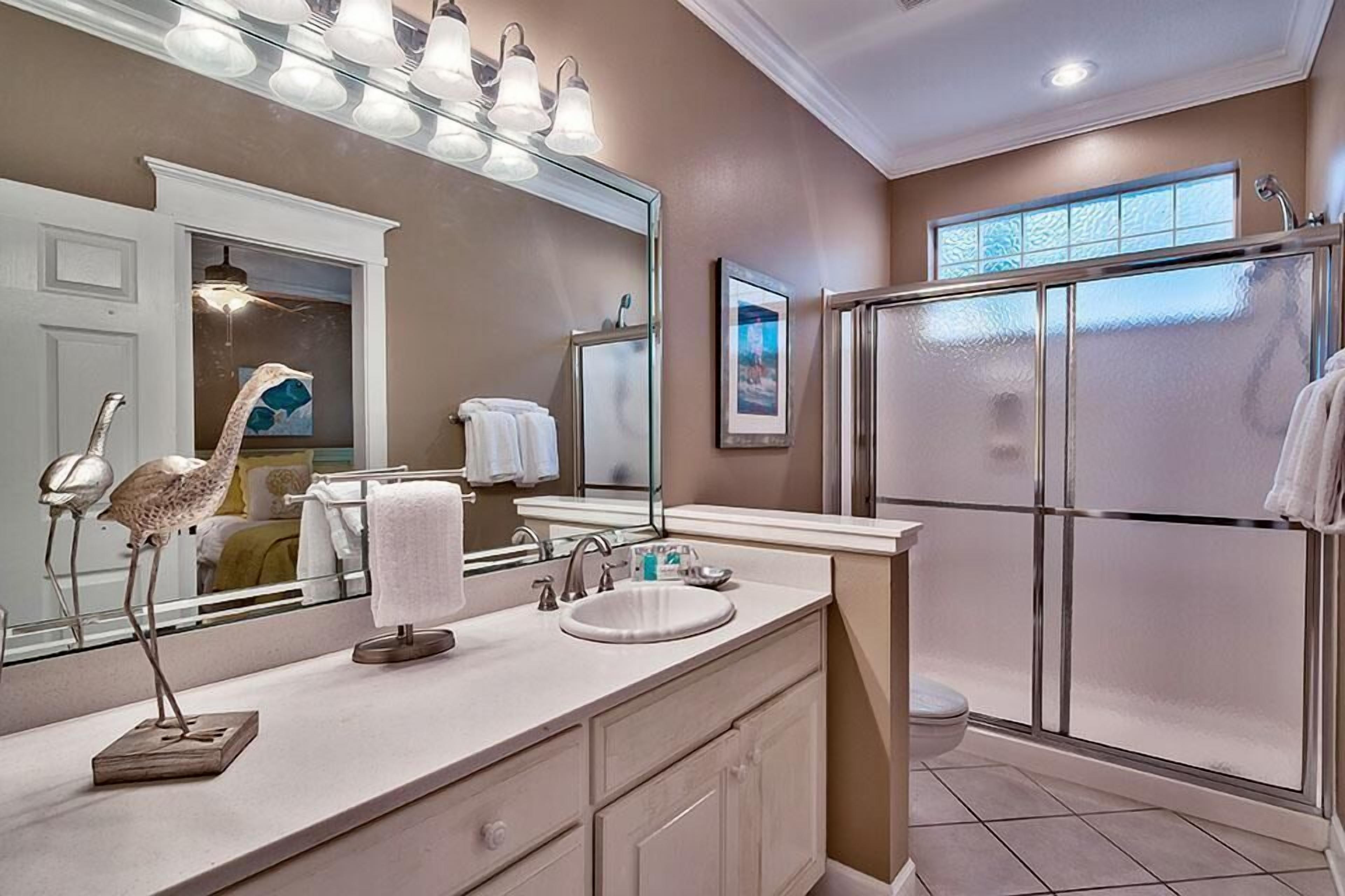A modern bathroom with a large mirror, vanity, and a walk-in shower.