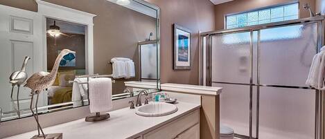 A modern bathroom with a large mirror, vanity, and a walk-in shower.