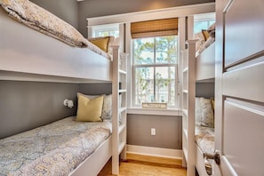 A dorm-style room with bunk beds, a window with a view of trees, and a small shelf with a sign. - Endless Grace 4 Bedroom Holiday Home by Five Star Properties (Santa Rosa Beach)