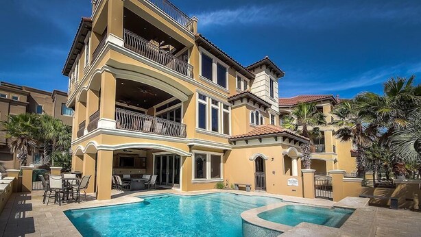 Un hotel de varios pisos con piscina, balcones y zona de estar al aire libre.