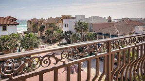 Un hotel frente al mar con balcones que dan al océano, palmeras y un paseo marítimo pavimentado.