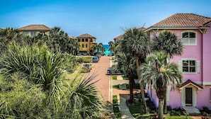 A residential street with houses, palm trees, and a clear blue sky.