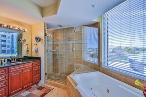 Une salle de bain moderne dotée d’une douche à l’italienne, d’une grande baignoire et d’un meuble-lavabo avec un miroir.