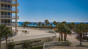 Un hôtel à plusieurs étages doté de balcons donnant sur une plage et l’océan.