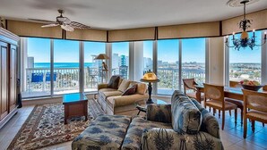 A spacious living room with a large window offering a city view, a ceiling fan, and a chandelier. - ST LUCIA 1006 3 Bedroom Holiday Home by Five Star Properties (Destin)