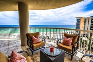 A balcony with two cushioned chairs, a small table with a candle, and a view of the ocean and beach. - ST MAARTEN 808 3 Bedroom Holiday Home by Five Star Properties (Destin)